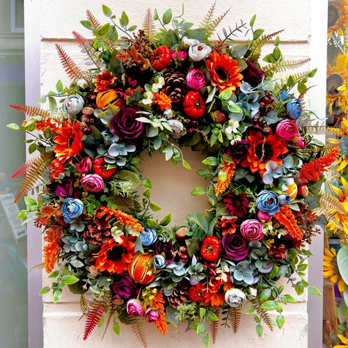 a large rich toned wreath with deep smoky blues, orange tones finished with foliage