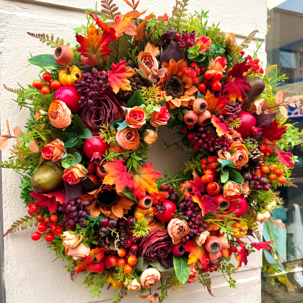 Colorful autumn wreath with flowers and fruits on a wall
