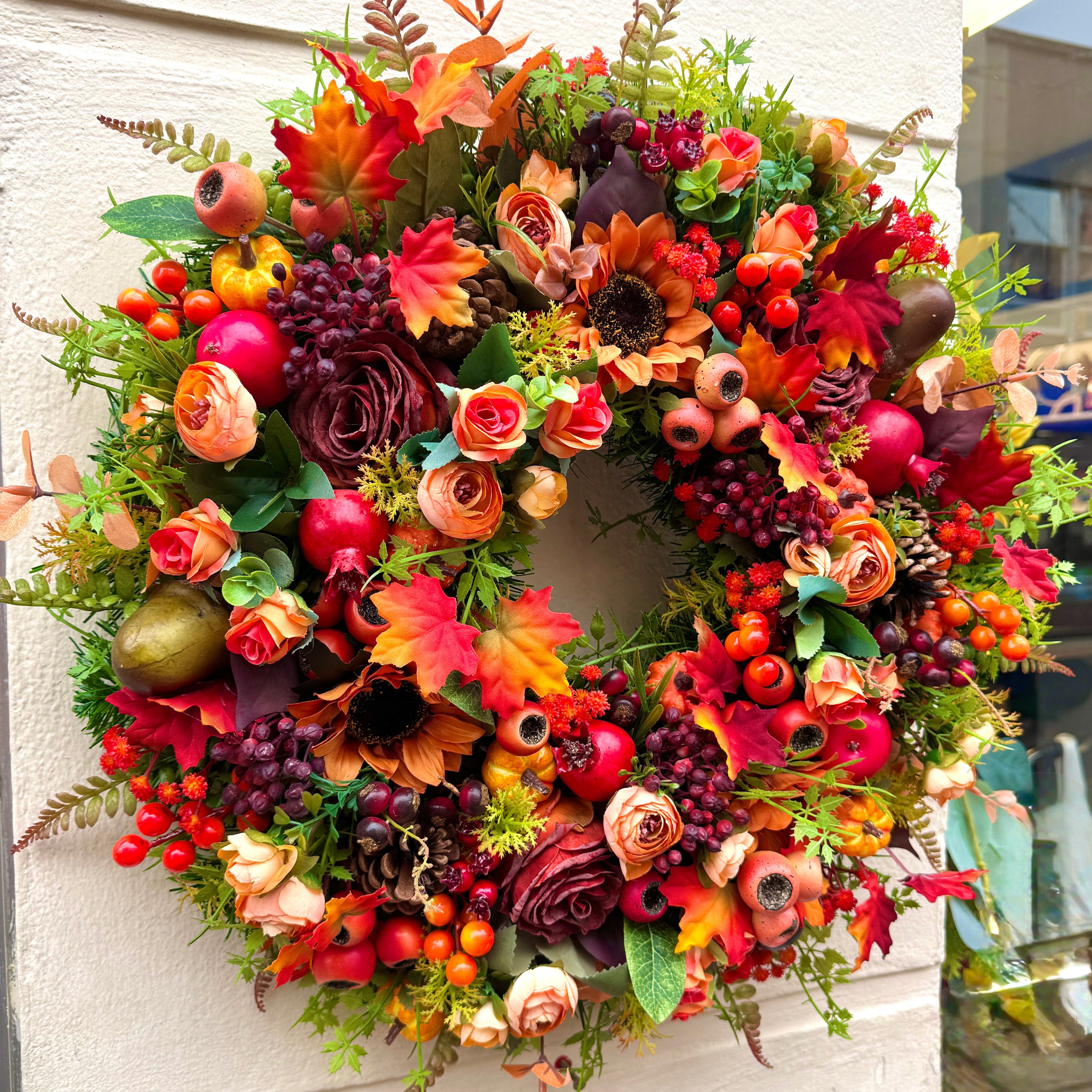 Colorful autumn wreath with flowers and fruits on a wall