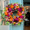 full front view of our cranorange artificial wreath, with vibrant orange ranunculus and deep cranberry peonies by jamesia blooms