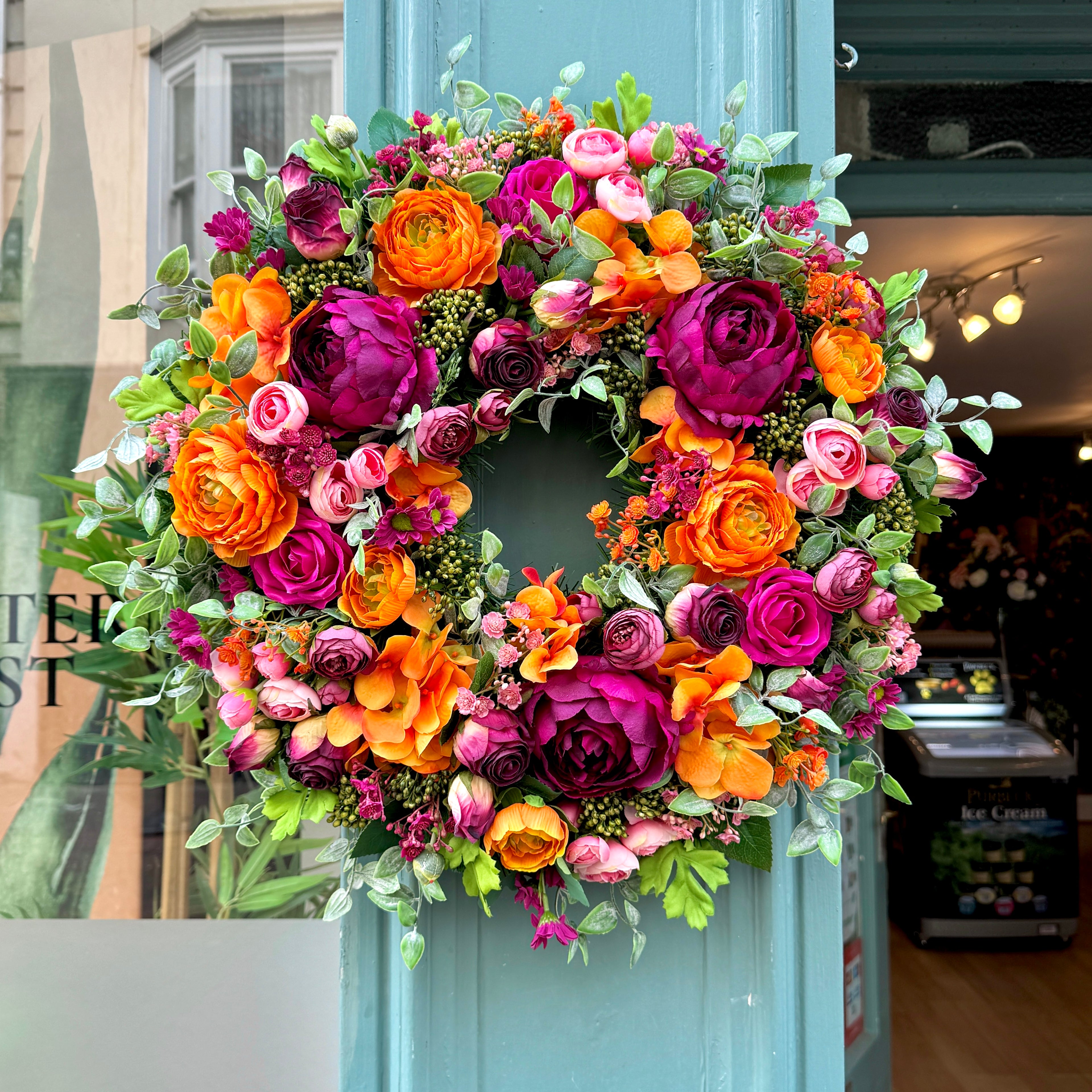 full front view of our cranorange artificial wreath, with vibrant orange ranunculus and deep cranberry peonies by jamesia blooms