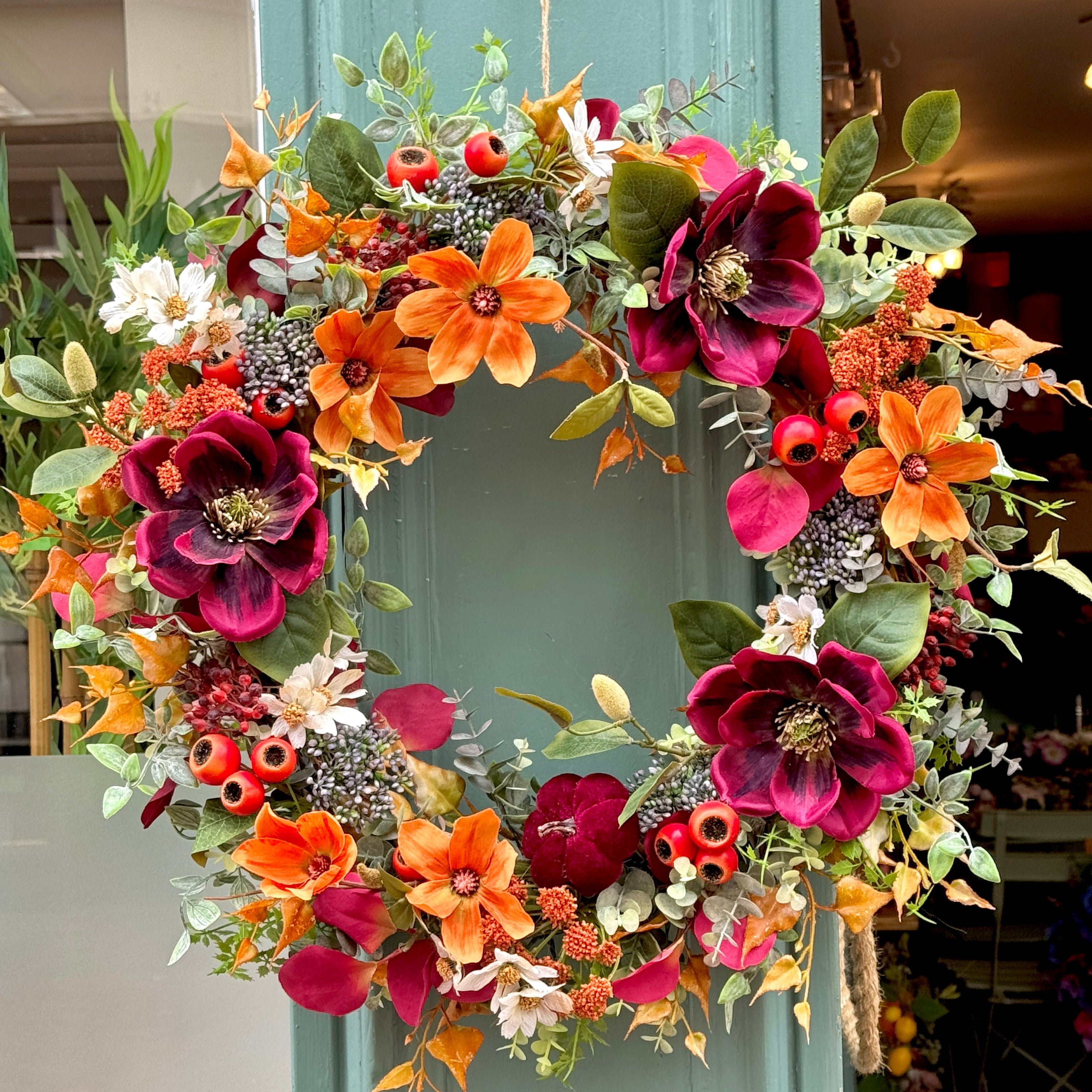 Colorful floral wreath with autumnal flowers on a green door.