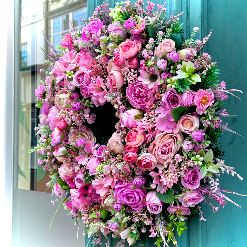 Floral wreath with pink and green flowers on a teal door