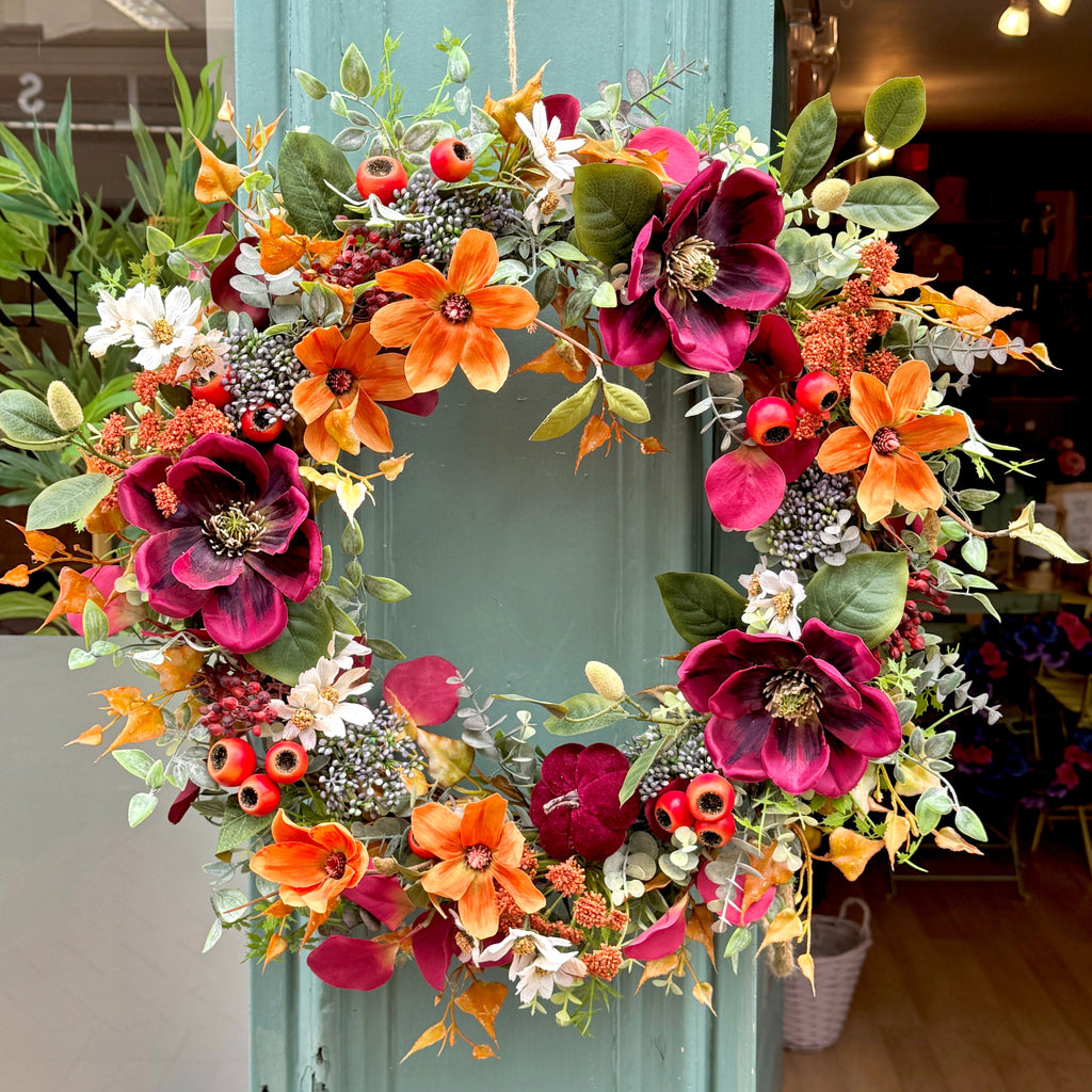 Colorful floral wreath on a green shop front with indoor setting