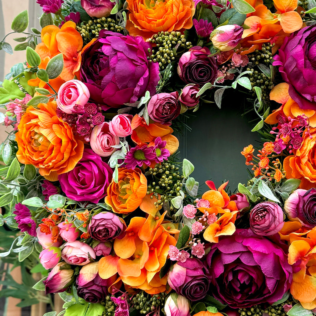 very close up of jamesia blooms cranorange wreath. Showing fine detail of premium faux flowers in orange cranberry and pink colours