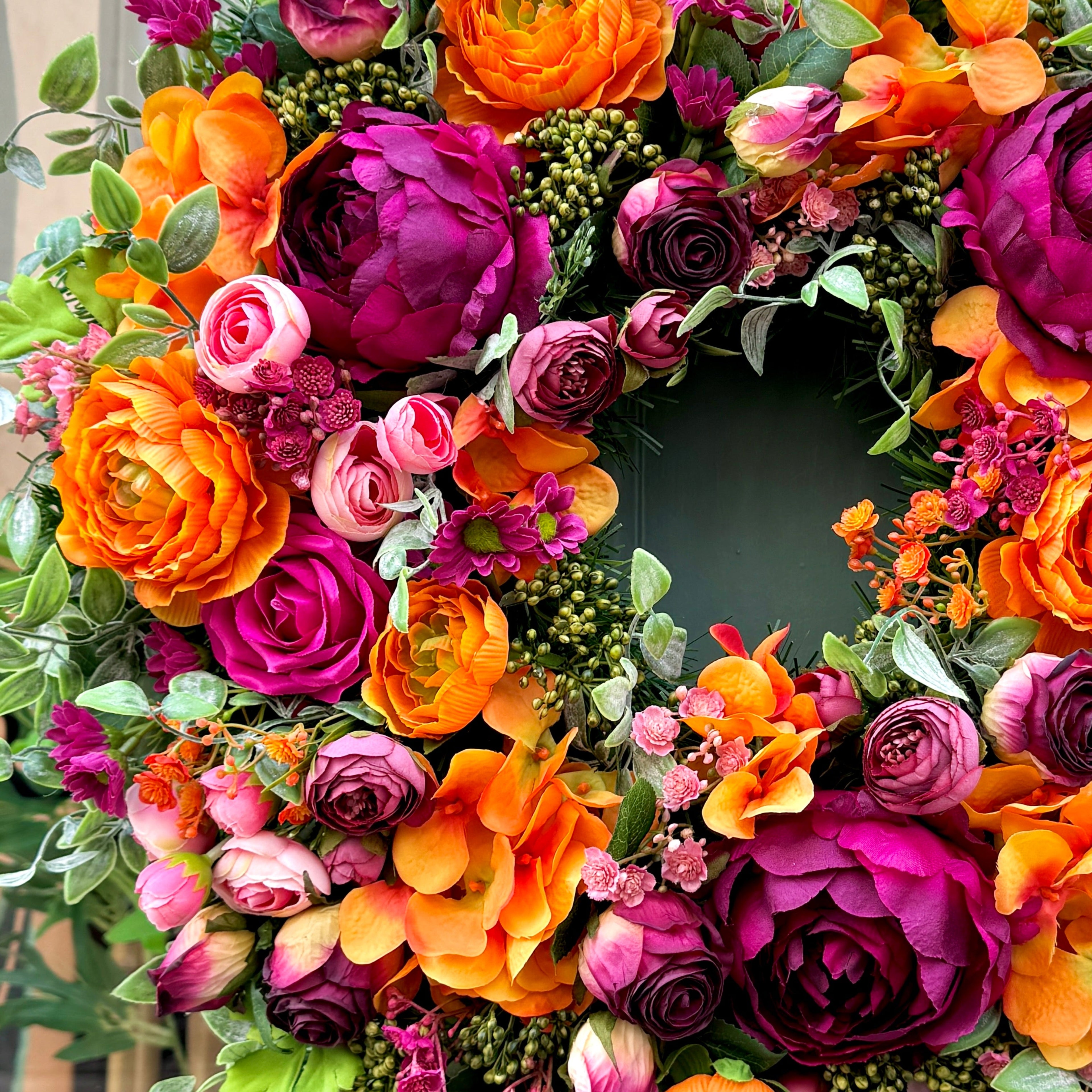 very close up of jamesia blooms cranorange wreath. Showing fine detail of premium faux flowers in orange cranberry and pink colours